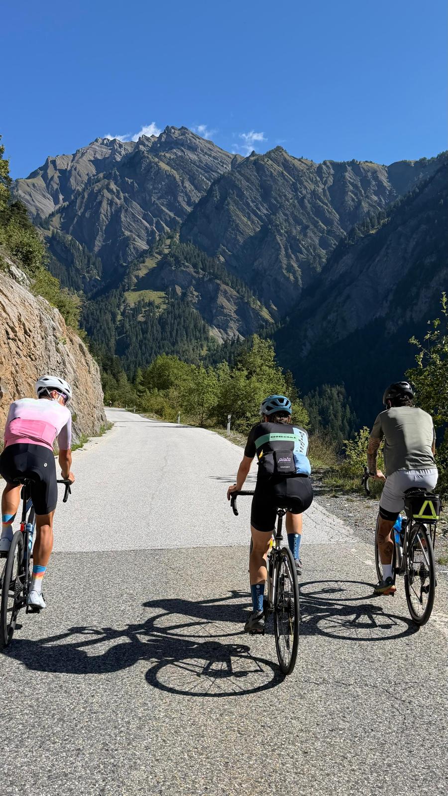 Three riders climbing together on an alpine pass road