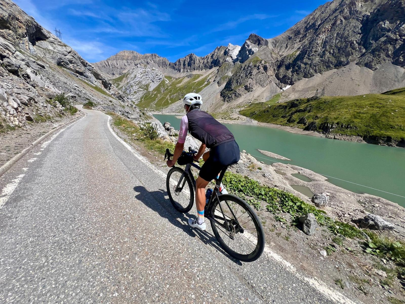 A rider climbing past the turquoise Lac de Sénin