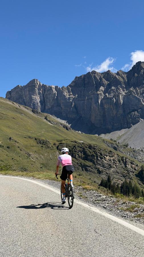 A rider climbing below a long wall of cliffs on the Sanetsch