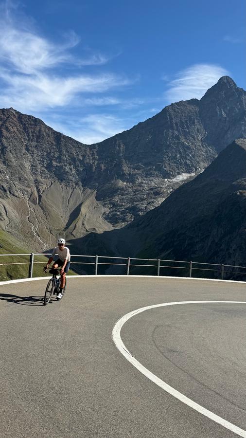 A rider coming round a hairpin on the Susten with peaks behind
