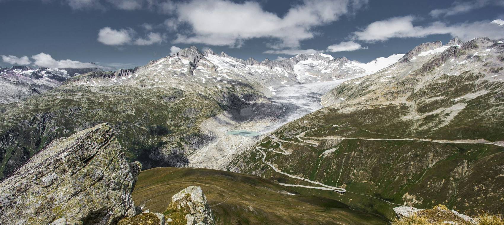 A wide view of a glacier and the pass road below it