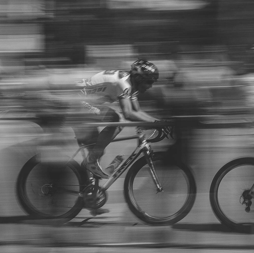 A cyclist riding hard, panned at speed